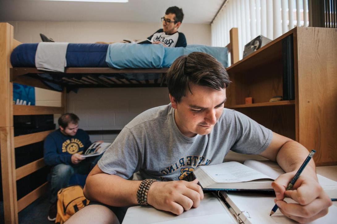 Three students studying together in a dorm room